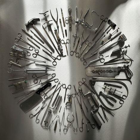 A circular arrangement of vintage surgical instruments—including scissors, forceps, scalpels, and a Captive Bolt Pistol—displayed on a light surface with soft shadows evokes the precision of Surgical Steel by Carcass.