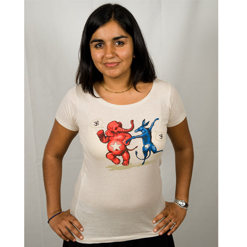 A woman smiles with her hands on her hips, wearing a Mantralogy activist tee in organic cotton. The light shirt shows cartoon red elephant and blue donkey boxing—ideal for expressing support at Chant4Change.