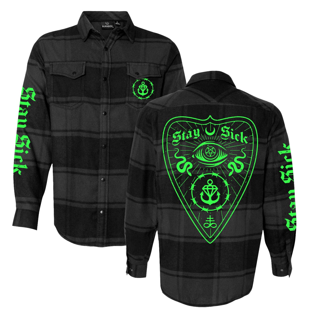 The Stay Sick Clothing black-grey flannel shirt features neon green Stay Sick text on the sleeves, a bold neon eye and anchor design on the back, with smaller anchor symbols on the front pockets—a modern twist on classic style.