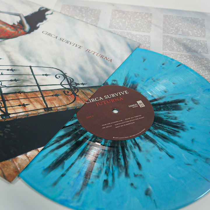 A limited edition Circa Survive vinyl in pale blue with black splatter is displayed alongside its illustrated album cover and a printed lyric sheet.