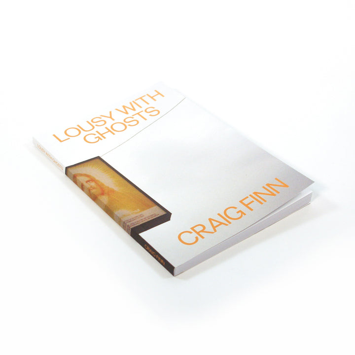 A limited edition book titled Lousy With Ghosts by Craig Finn is displayed on a white background, featuring a mostly white cover with orange text and a small rectangular image of a person near the spine. Brand: Craig Finn.