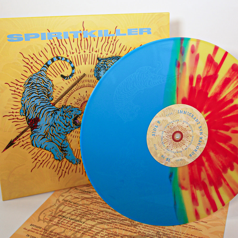 A blue and red-yellow splatter Spiritkiller vinyl sits before an album cover with two blue tigers and the bold yellow SPIRITKILLER title. The hardcore band’s lyric or info sheet is partially visible below.