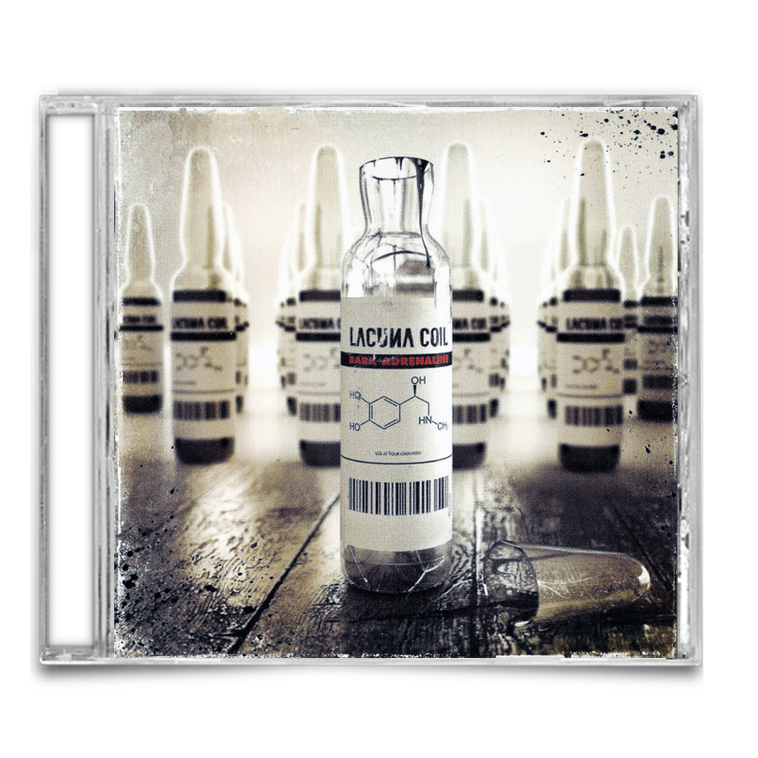 A CD case shows a vial labeled Lacuna Coil, with chemical formulas and surrounded by vials referencing “Kill The Light,” all set on a worn, reflective surface. The background is blurred to highlight the main Lacuna Coil vial.