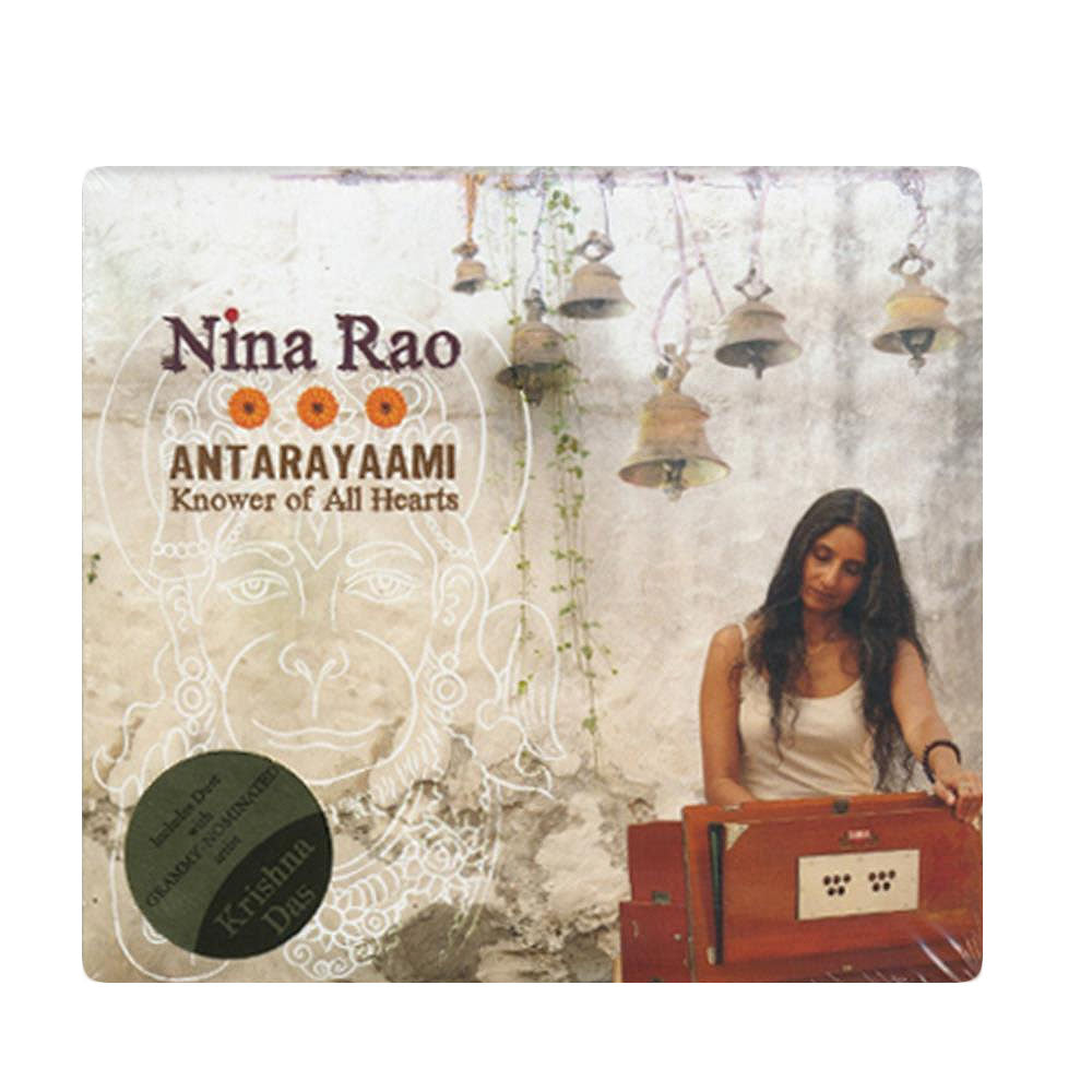 Album cover of Nina Rao playing harmonium by a mural, with text: “Nina Rao ANTARAYAAMI Knower of All Hearts.” Green sticker notes Krishna Das. Released by Mantralogy/Gaura Vani. Ideal for fans of chanting and devotional music.