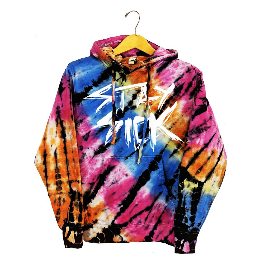A vibrant Stay Sick Clothing tie-dye hoodie in pink, blue, yellow, orange, and black with bold, slanted white STAY SICK text on the front, shown on a wooden hanger.