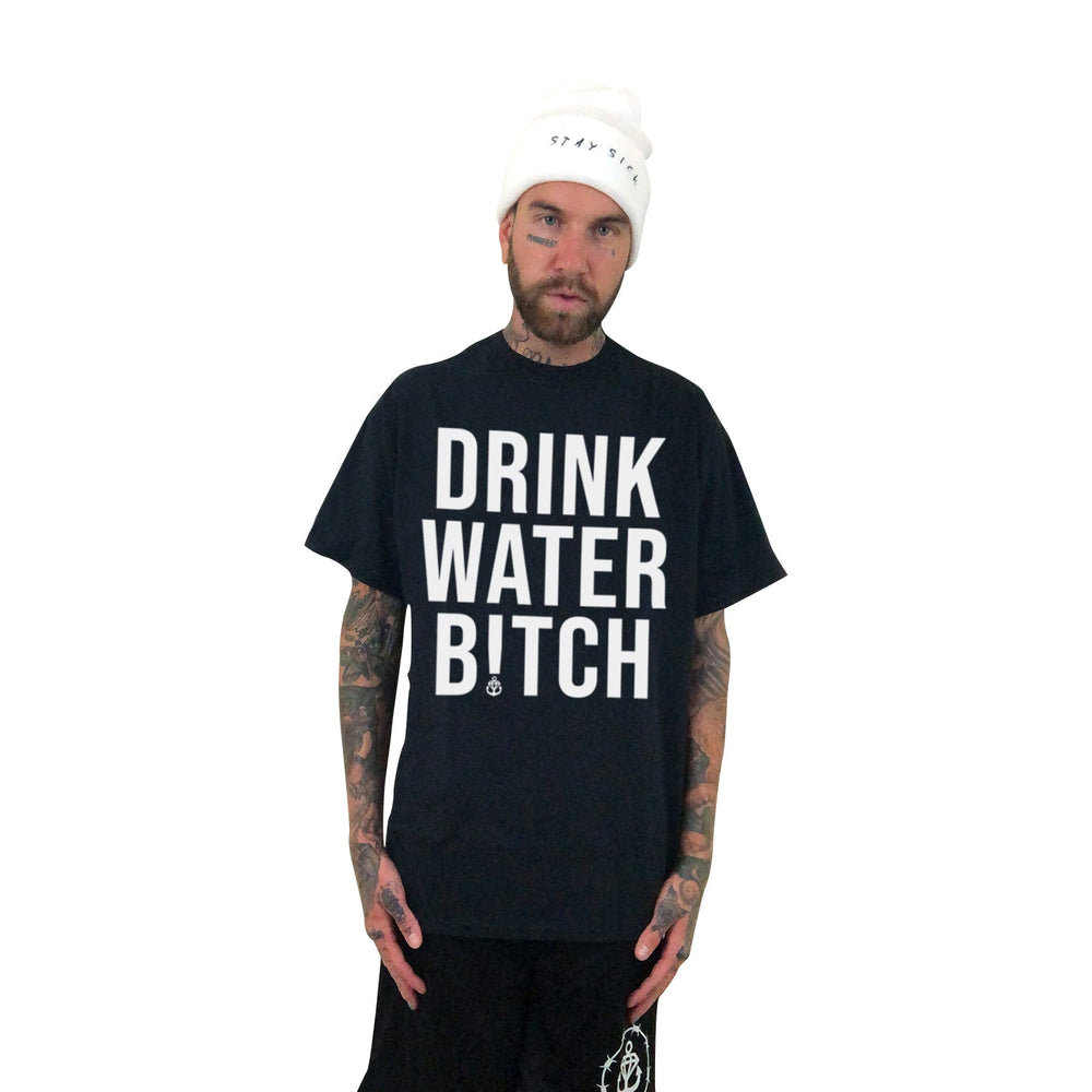 A tattooed man in a white beanie and Stay Sick Clothing’s bold black “DRINK WATER BITCH” tee stands against a white background, confidently promoting hydration with the brand’s unapologetic message.