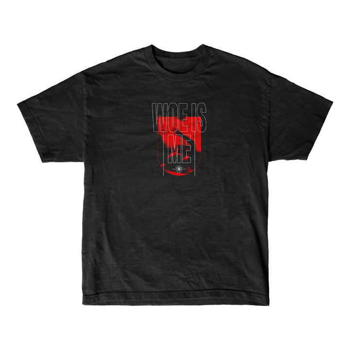 A black Woe Is Me Daybreak t-shirt featuring WOE IS ME in bold white and red letters on the front, with a dramatic dripping effect on the red text.