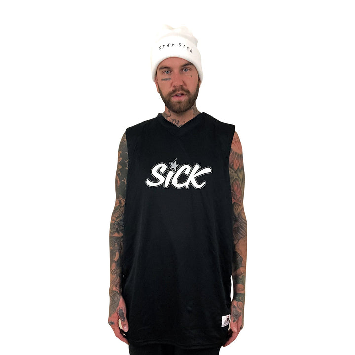 A tattooed, bearded man models edgy streetwear from Stay Sick Clothing: a white beanie with “STAY SICK” and a sleeveless black tee with “SICK” in bold on the front, all set against a plain white background.