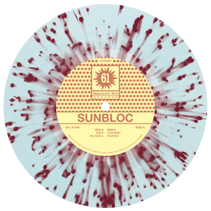 A vinyl record with a light blue background and red splatter pattern. The center label reads Sunbloc, an alternative music release featuring bold yellow and red track titles. Brand: Sunbloc.