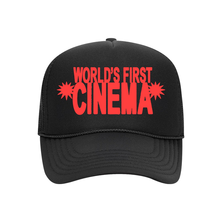 A black trucker hat by World's First Cinema with a stacked logo, bold red WORLDS FIRST CINEMA text, and starburst designs flanking the word CINEMA.