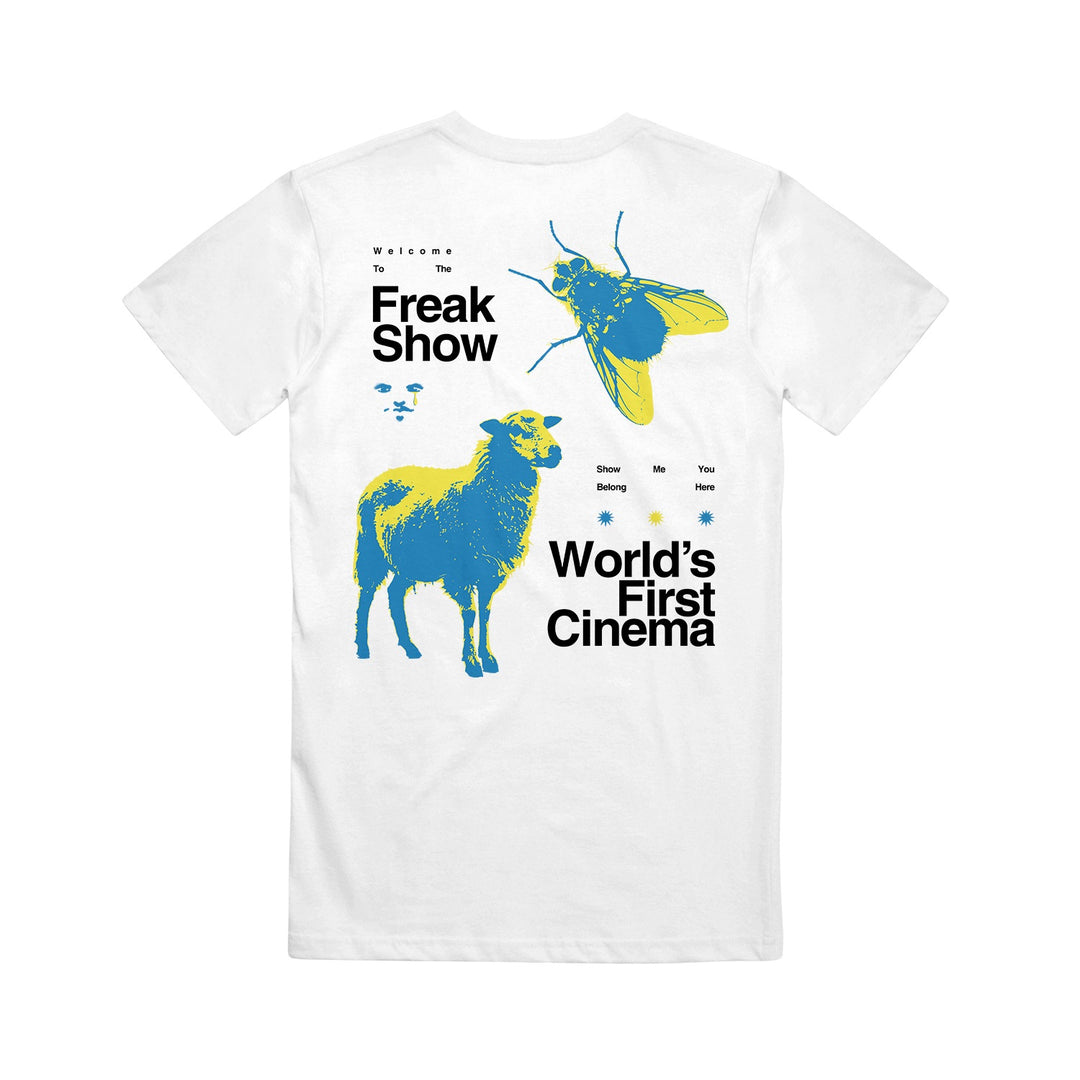 A white World's First Cinema Comfort Colors T-shirt with a blue and yellow sheep and fly graphic, black "Welcome to the Freak Show" text, and "Show Me You Belong" detail—a standout piece for unique shirt lovers.