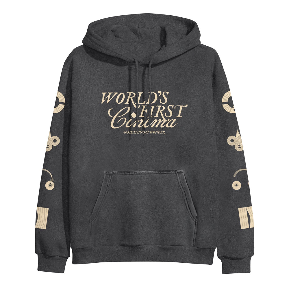 A black World's First Cinema midweight pullover hoodie with beige sleeve designs, a front pocket, "WORLDS FIRST CINEMA" in large chest letters, and "SOMETHING OF WONDER" beneath.
