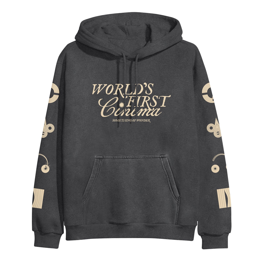 A black World's First Cinema midweight pullover hoodie with beige sleeve designs, a front pocket, "WORLDS FIRST CINEMA" in large chest letters, and "SOMETHING OF WONDER" beneath.