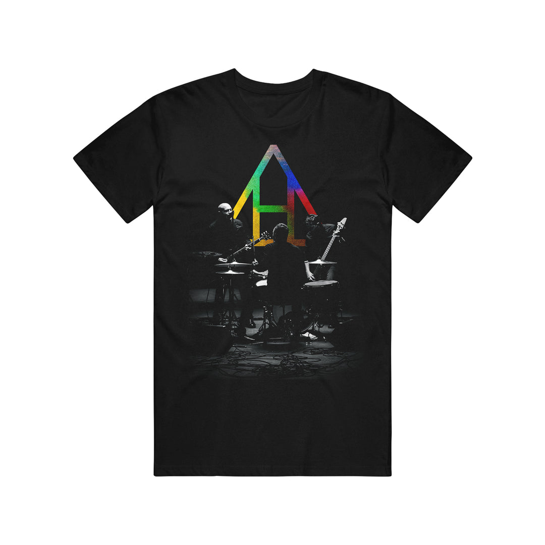 HELD Black Comfort Colors t-shirt with a colorful geometric A above a grayscale image of three musicians on stage—ideal for fans of unique printed tees.