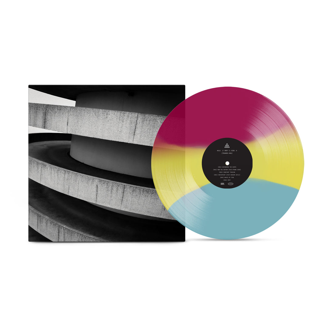 A HELD vinyl record in magenta, yellow, and blue rests partly outside a square cover with a black-and-white curved concrete structure photo, evoking the style of Frank Iero’s BROKEN SPACESUIT.