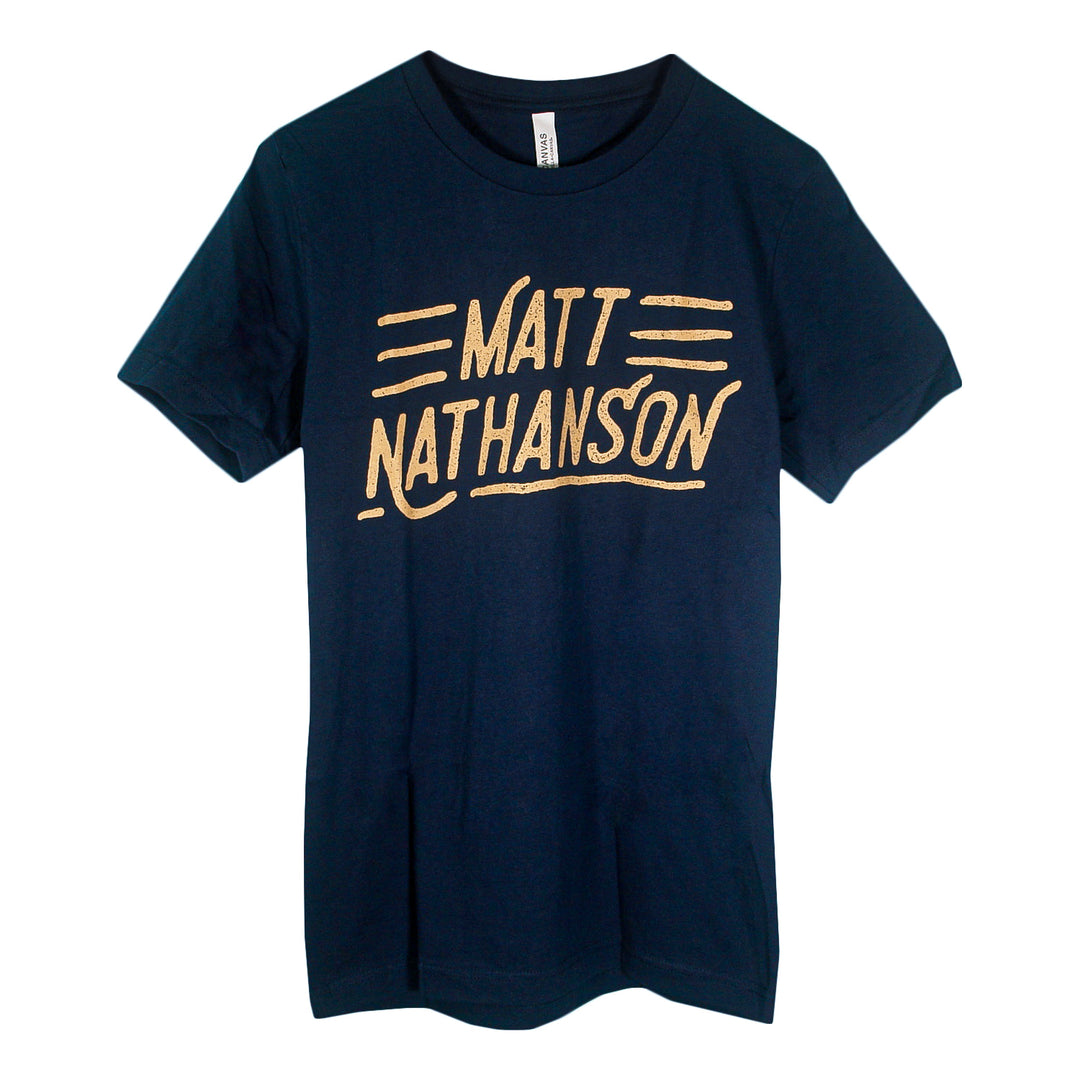 A navy blue Matt Nathanson T-shirt with the artist’s name in large yellow handwritten letters, highlighted by three yellow lines above and below. A stylish pick for fans of bold printed tees. Brand: Matt Nathanson.