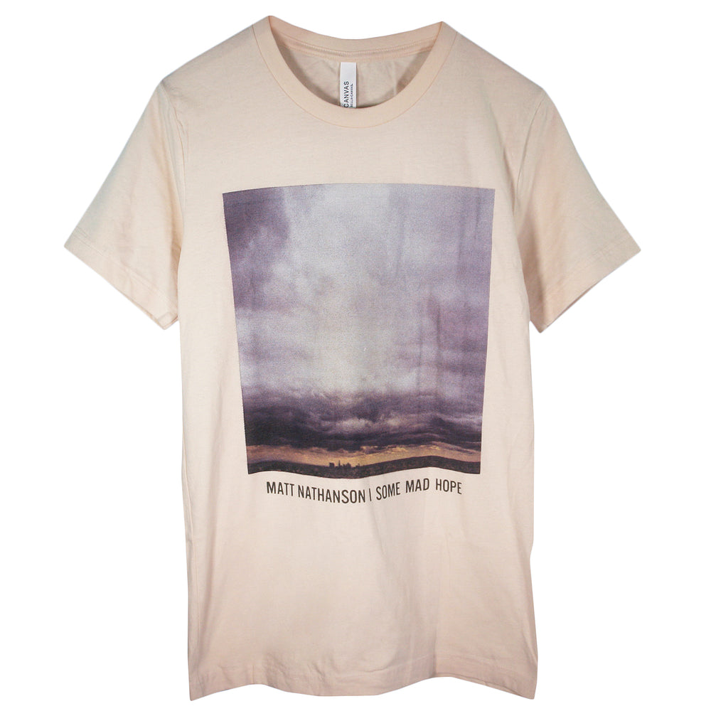 A beige Matt Nathanson T-shirt with a square image of a cloudy sky over a landscape and MATT NATHANSON | SOME MAD HOPE text below—ideal for fans of unique, custom-printed tees.