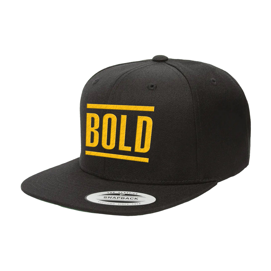 The Bold brand snapback cap features a black design with "BOLD" in large yellow letters on the front panel and a flat brim for a modern, stylish look.