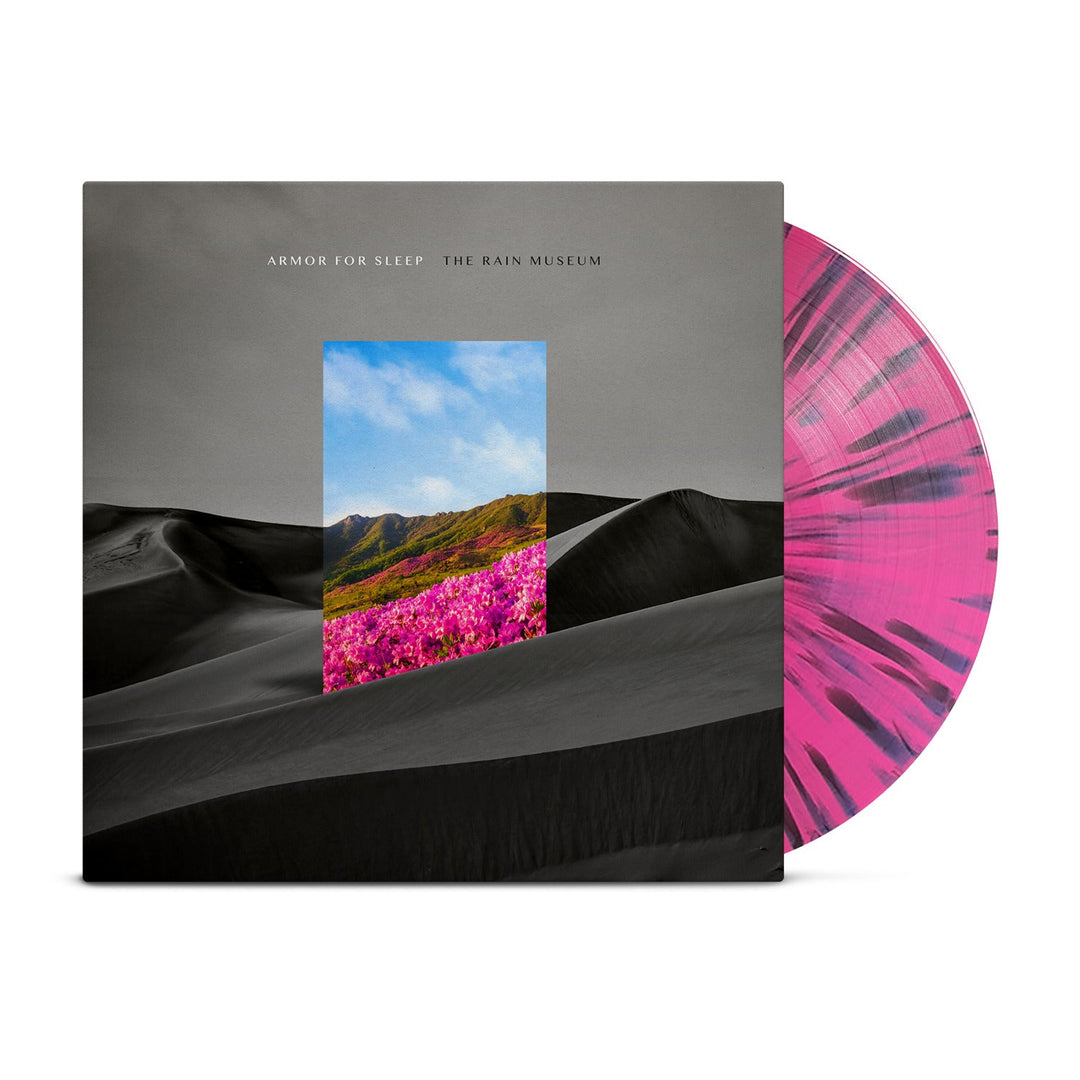 A hot pink vinyl with black splatter from Armor For Sleep slides out of its sleeve, which features a black and white desert landscape, colorful flowers in a window, distant mountains, and “The Rain Museum” text.
