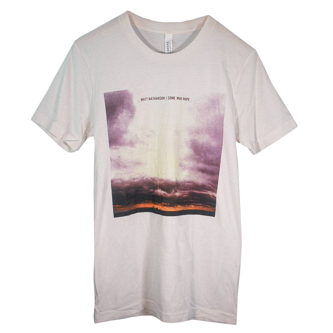 A Matt Nathanson white T-shirt with a rectangular print of a purple and orange cloudy sunset sky and “MATT NATHANSON SOME MAD HOPE” in small text above the image.