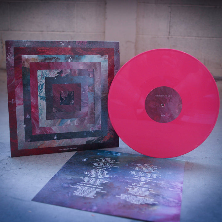 A pink vinyl record by Axis is shown beside its square album cover with abstract, layered square designs in muted tones, evoking the band's almighty-heavy sound. A lyric sheet with white text is placed in front.