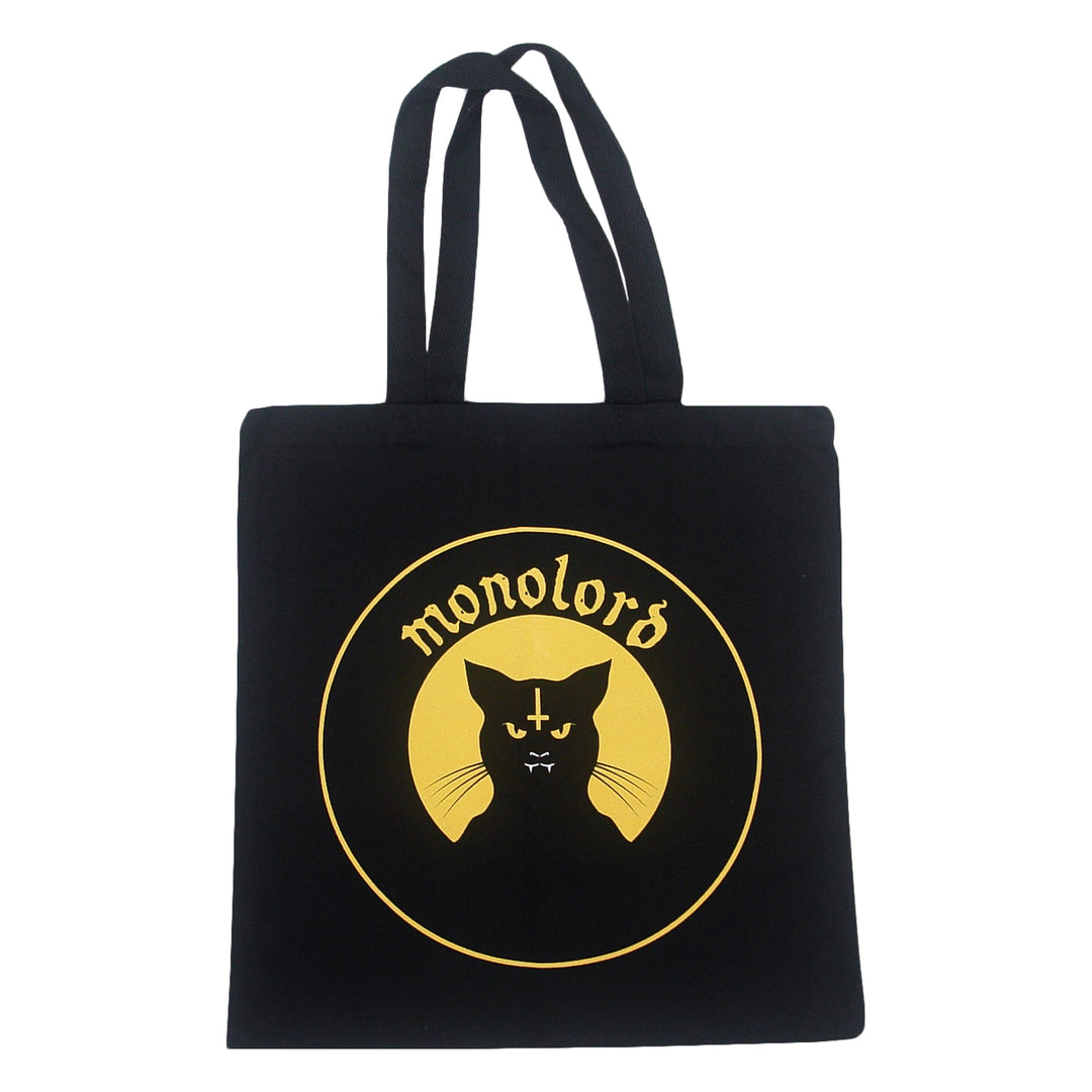 Black heavy cotton canvas tote bag featuring a gold circular graphic of a cat with an inverted cross on its forehead and the text monolord arched above it.