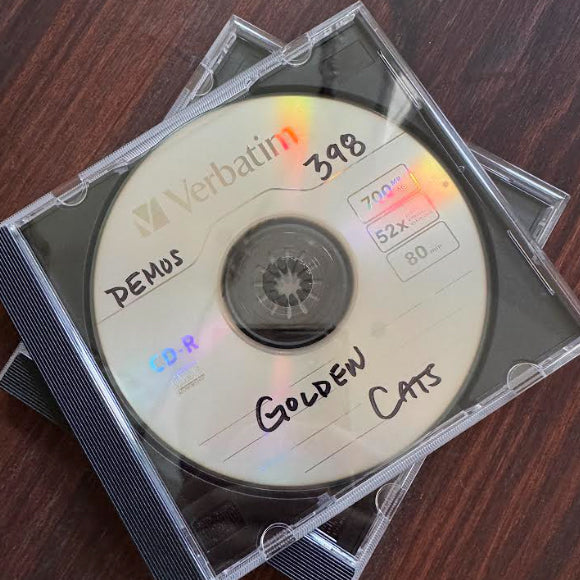 A Verbatim CD-R in a clear plastic case featuring handwritten DEMOS and GOLDEN CATS labels on the disc.