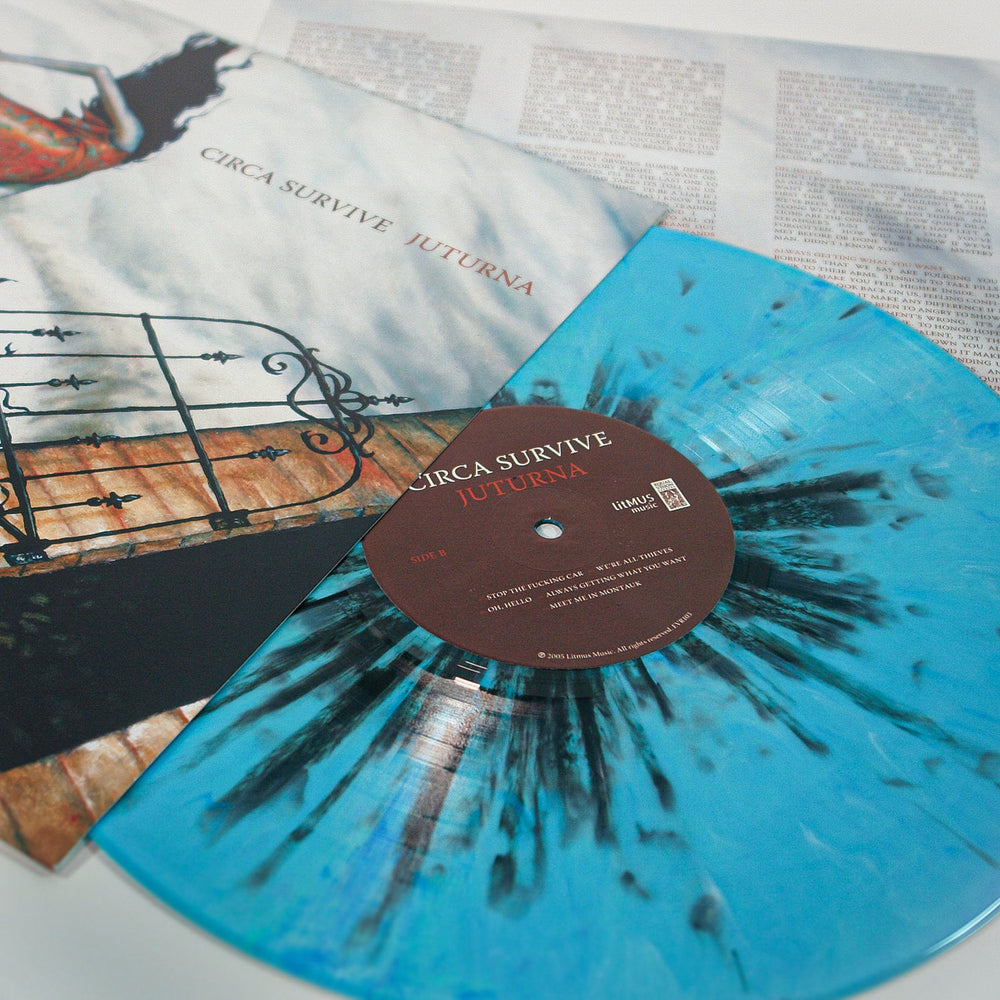 A limited edition Circa Survive vinyl in pale blue with black splatter is displayed alongside its illustrated album cover and a printed lyric sheet.