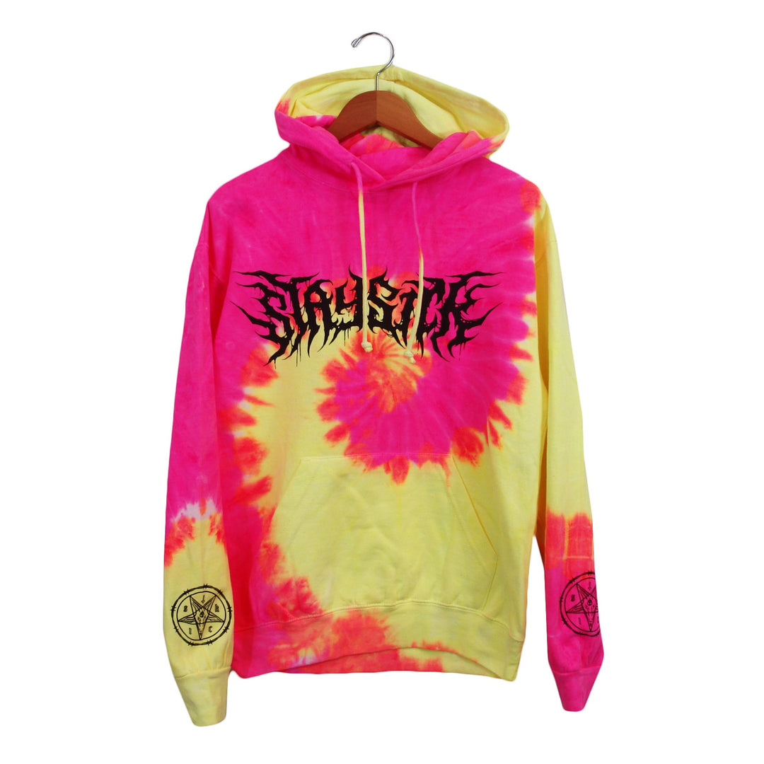 A pink and yellow fluorescent swirl tie-dye hoodie from Stay Sick Clothing features a black, spiky Death Cvlt logo on the chest and circular black symbols on both sleeves, displayed on a wooden hanger against a white background.