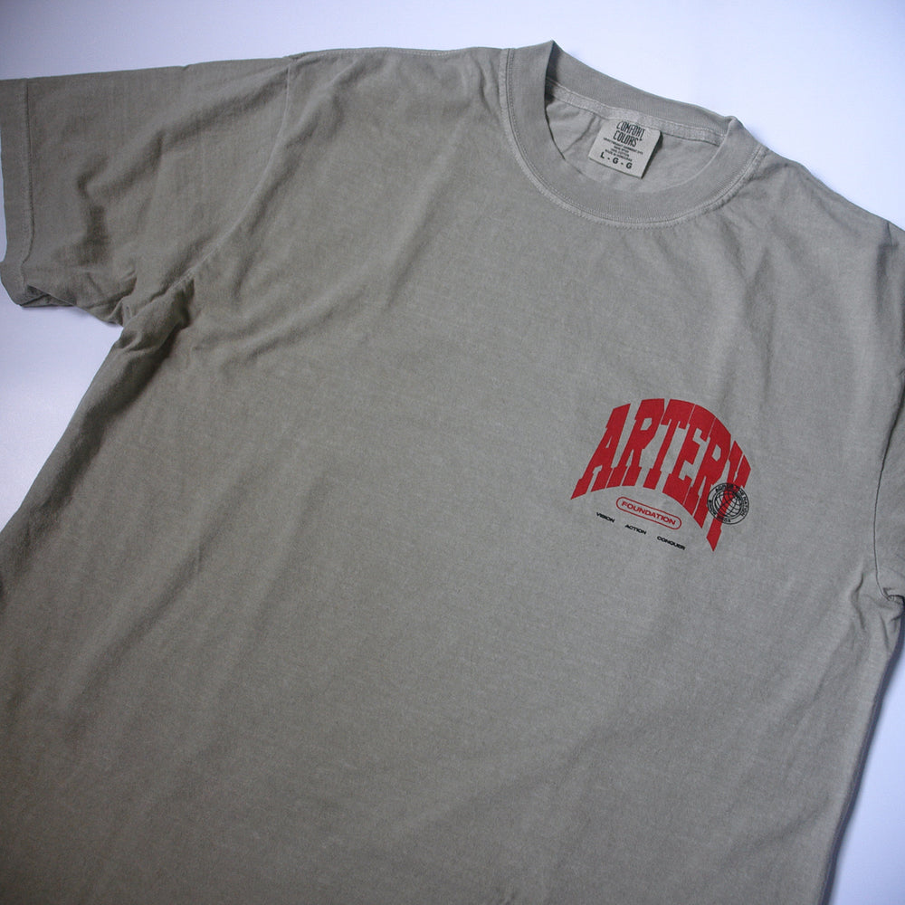 A light gray, garment-dyed Artery Foundation T-shirt with "ARTERY" in bold red and small black graphics and text printed below it on the left chest.
