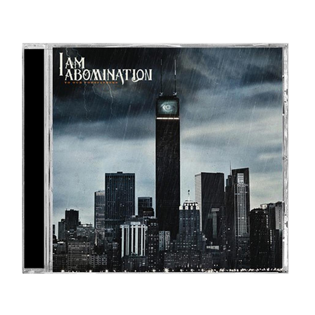 A CD cover for I Am Abomination features a dark, rain-soaked city skyline with an eerie eye near the top of the tallest building. The brand name "I Am Abomination" and the album title "Invisible Titans" are displayed in white at the top left.