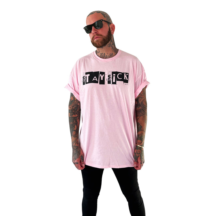 A tattooed man wearing sunglasses and a light pink Stay Sick Clothing T-shirt with STAY SICK text stands against a plain white background.