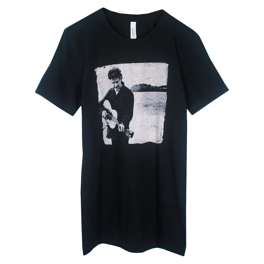 Black T-shirt from Matt Nathanson featuring a black-and-white image of a person playing guitar outdoors with water and land in the background—a standout addition to your printed T-shirt collection.