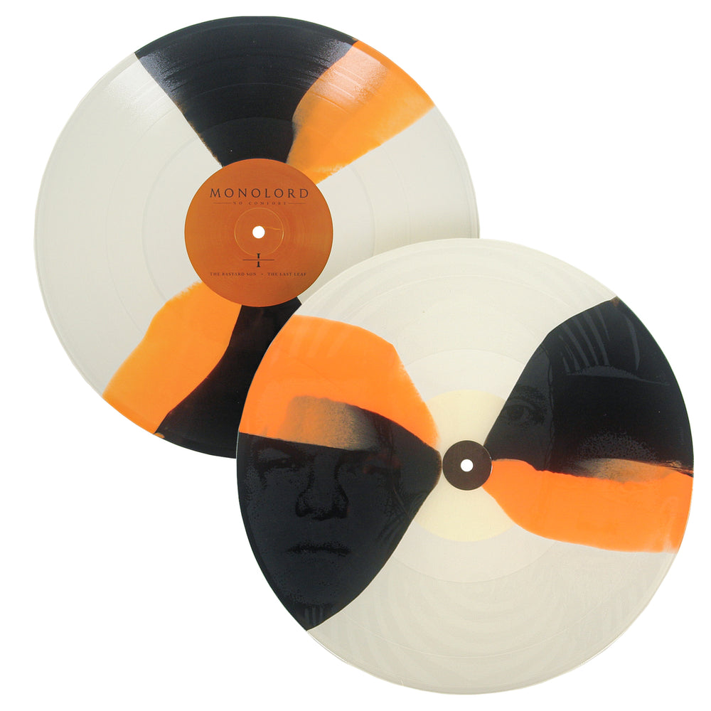 Two No Comfort vinyl records with a cream, orange, and black swirl pattern; one features a Monolord record label, and the other features a black-and-white portrait image printed on the surface.