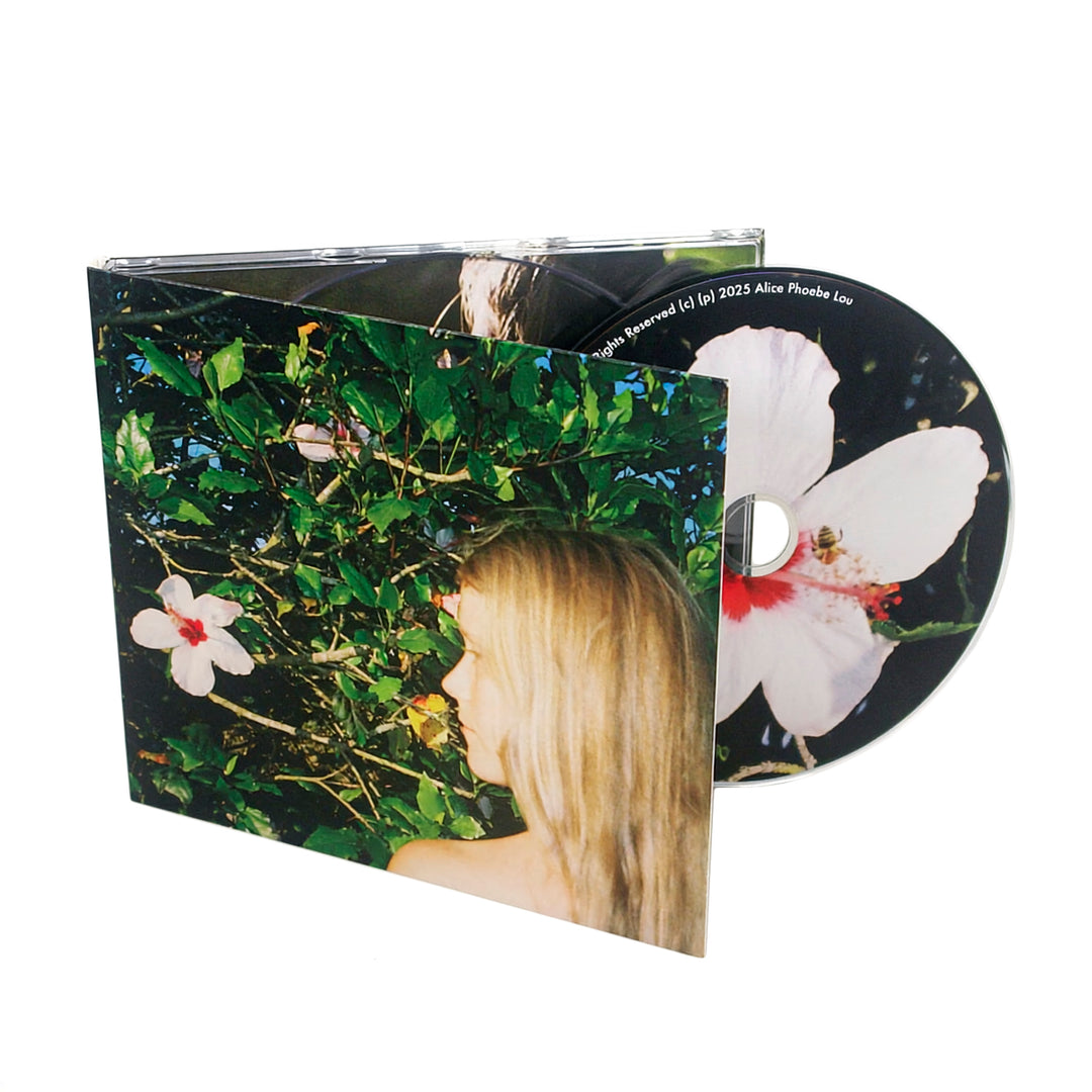 A CD and its case featuring a cover photo of a person with long blond hair surrounded by green leaves and large white flowers with pink centers, evoking the serene mystique of a Mind Reader. The CD shows a close-up of one of the flowers with a bee on it.
