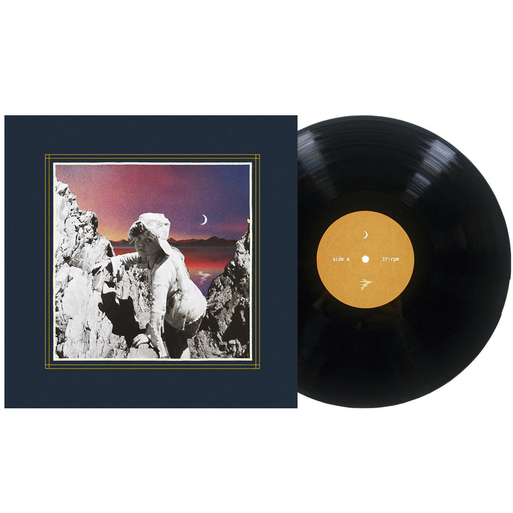 A vinyl record next to its cover, which features a classical statue among rocky mountains with a crescent moon in a colorful dusk sky, as distant galaxies shimmer above the serene landscape.
