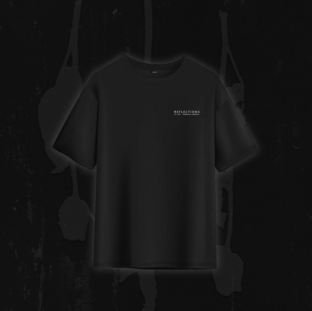A plain black T-shirt from Reflections, featuring the word "REFLECTIONS" in white text on the left chest, inspired by the instrumental versions of Crystal Eyes and displayed against a dark, abstract background evocative of digital downloads.