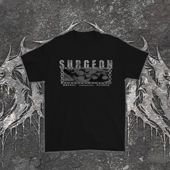 Black Petunia t-shirt featuring a rectangular graphic with the word SURGEON above metallic medical instruments framed by a chain, with MMXXIII printed below.