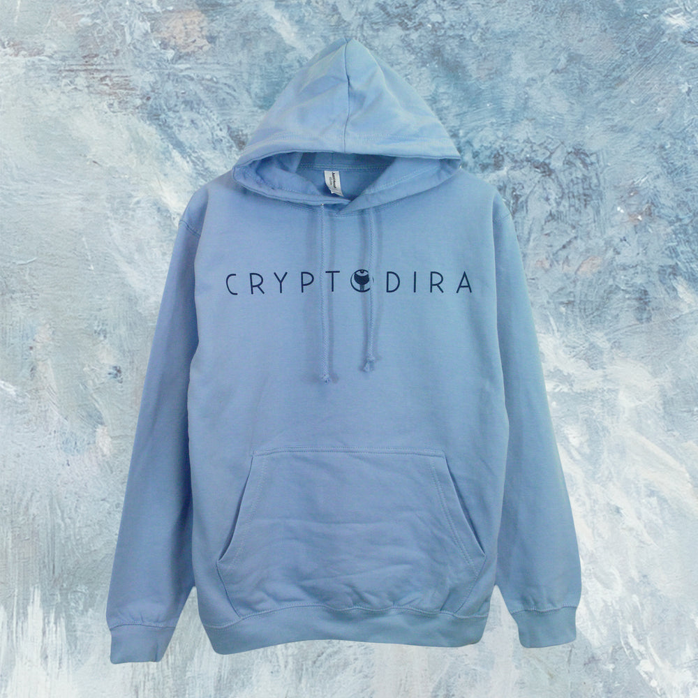 A light blue Cryptodira pullover hoodie made from soft ringspun cotton, featuring "CRYPTODIRA" in black letters across the chest, hangs against a textured blue and white painted background.