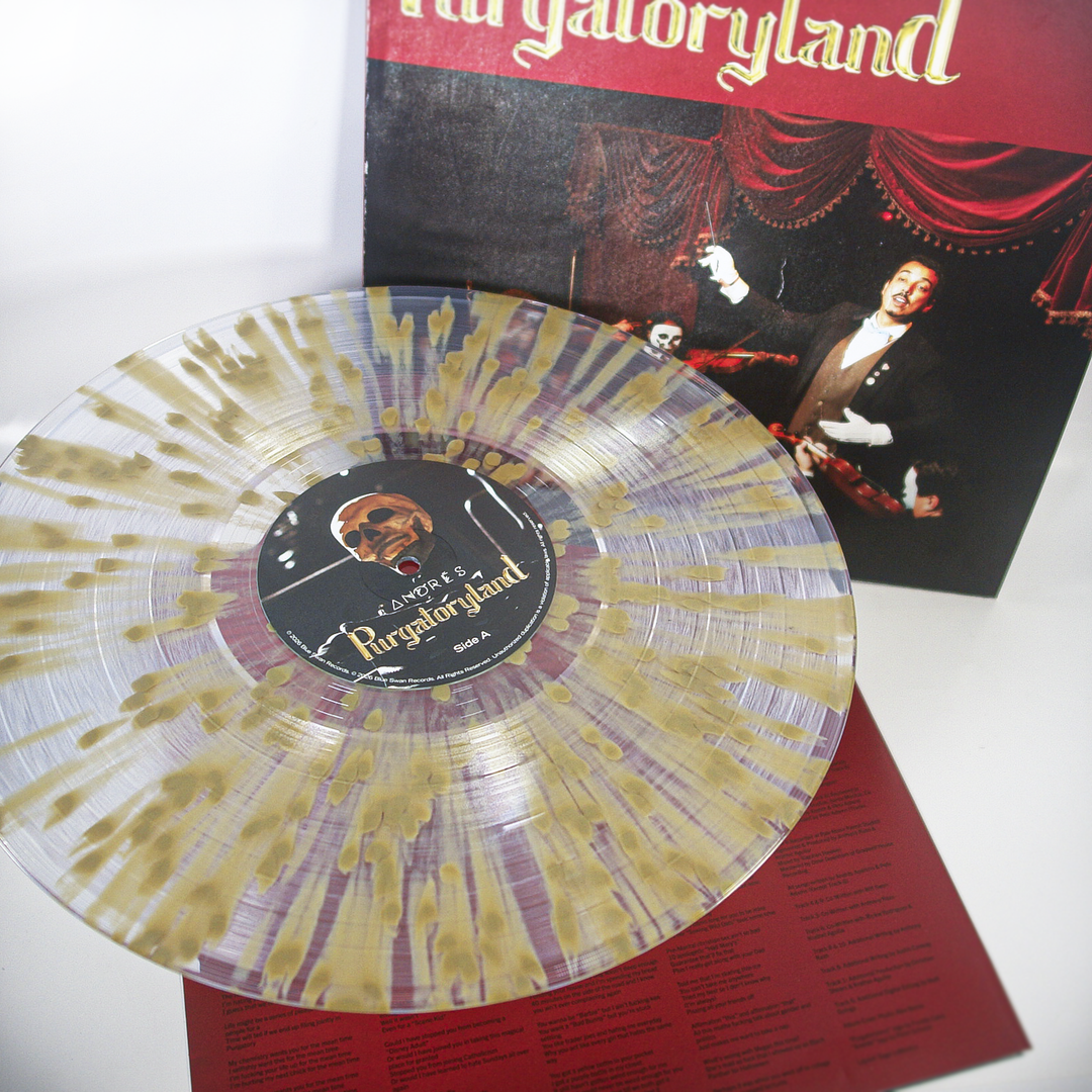 A translucent limited edition Andrés vinyl with gold splatter design rests on a red sheet with text, in front of the Purgatoryland album cover featuring a theatrical performer.
