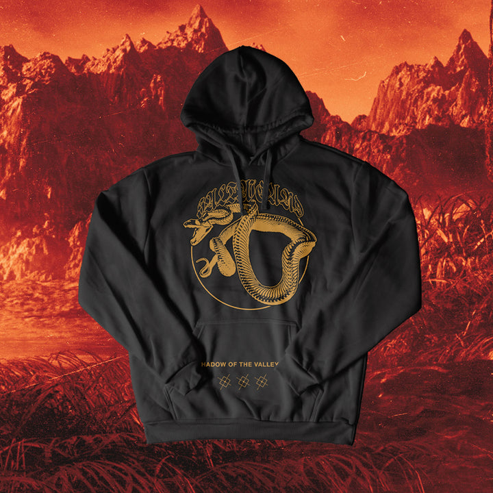 A Saltwound black pullover hoodie with a large gold snake and "SHADOW OF THE VALLEY" text, in classic fit Gildan Heavy Blend, is shown against a red mountainous landscape.
