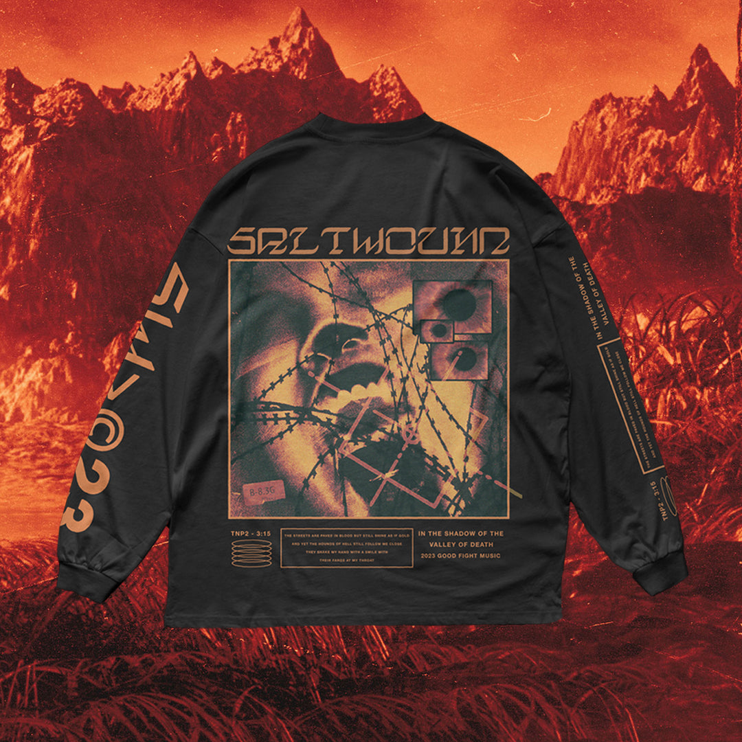 A black Saltwound long sleeve American Apparel shirt with abstract barbed wire art, cryptic text, and graphics on the back, photographed against surreal red mountains. Made from 100% cotton for comfort.