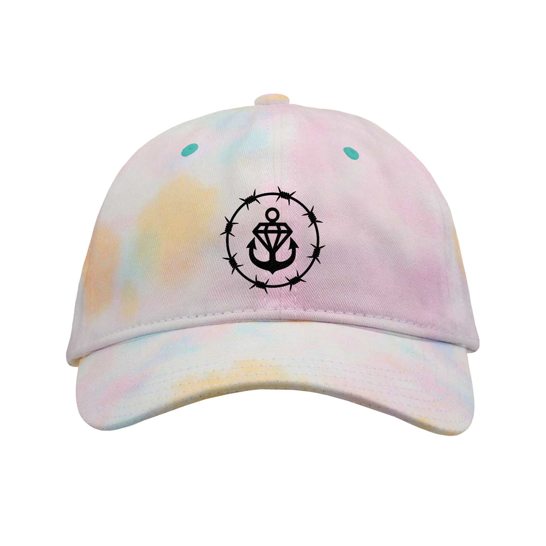 A pastel Sorbet Tie-Dye Dad Hat from Stay Sick Clothing, featuring a black anchor and heart emblem encircled by barbed wire on the front.