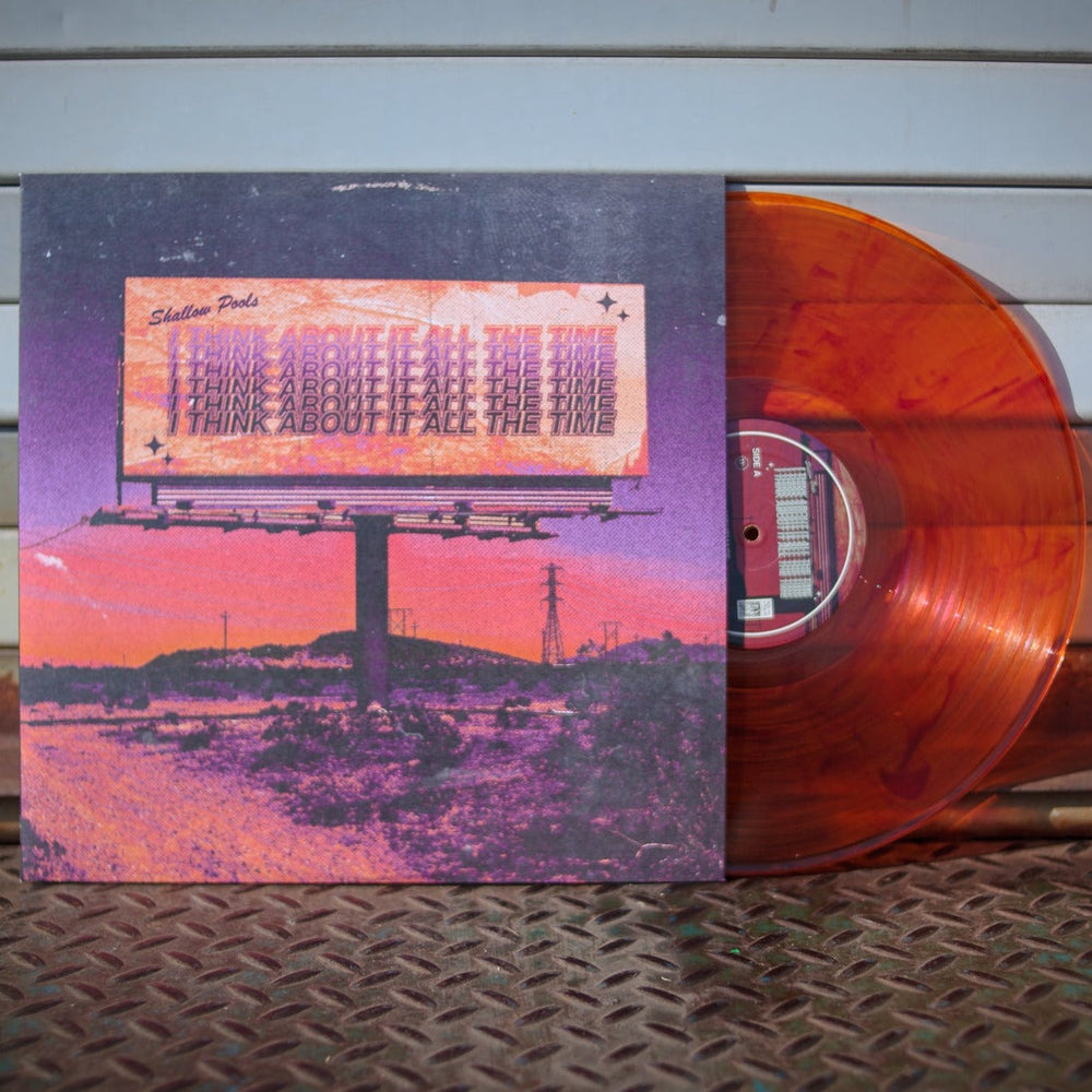 A vibrant Yellow/Orange Marble LP from Shallow Pools’ limited edition of 250 is partially slid out of a cover featuring a billboard that reads I THINK ABOUT IT ALL THE TIME set against a pink and purple landscape.