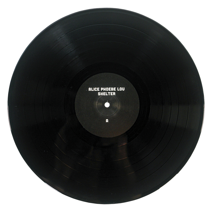 A black vinyl record of Alice Phoebe Lou’s fifth studio album, Shelter, featuring a center label marked with the letter A, is shown against a white background.