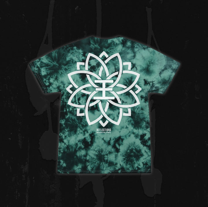 A green and black tie-dye T-shirt from Reflections, featuring a large, intricate white geometric flower design with the word "REFLECTIONS" printed below. Inspired by the instrumental version of “Crystal Eyes,” this unique merch is ideal for fans looking for digital downloads or standout apparel. The shirt is showcased against a dark background.