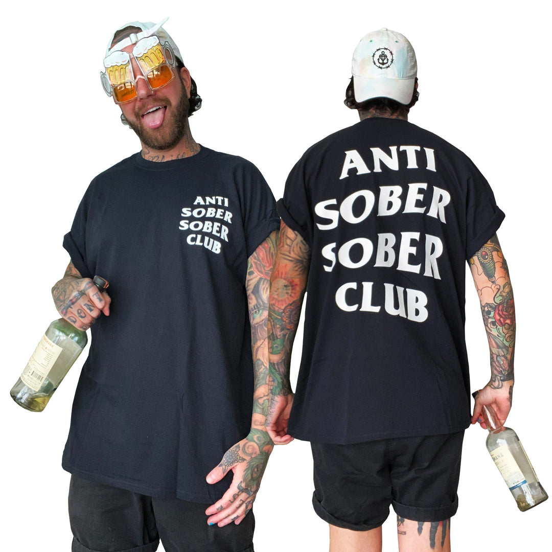 A tattooed individual wears a Stay Sick Clothing Anti-Sober Club Black T-Shirt with ANTI SOBER SOBER CLUB on the front, holds a bottle, and sports beer-shaped glasses. Both the tees bold front and back are shown.