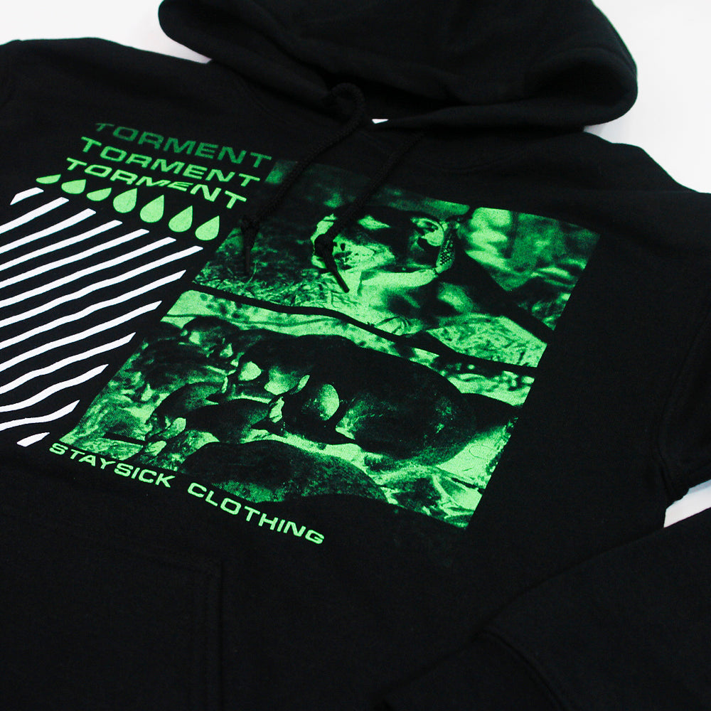 Black hoodie by Stay Sick Clothing featuring green graphic frogs, TORMENT repeated three times, diagonal white stripes, green droplets, and STAYSICK CLOTHING text—capturing the intriguing essence of Torment Black.