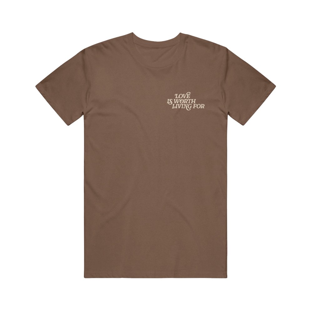 The Joshua Bassett Espresso Tee is a plain brown shirt with "LOVE IS WORTH LIVING FOR" in white text on the left chest, displayed in a clean font and laid flat on a white background.