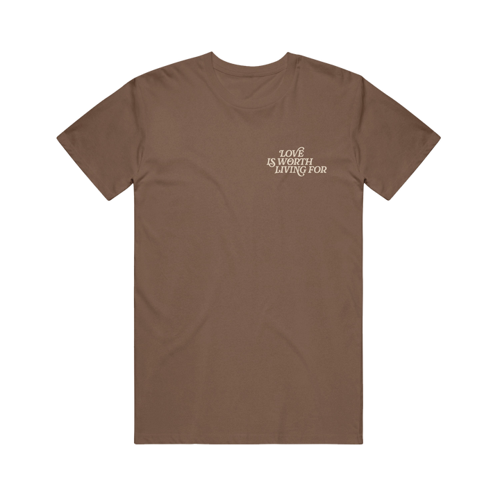 The Joshua Bassett Espresso Tee is a plain brown shirt with "LOVE IS WORTH LIVING FOR" in white text on the left chest, displayed in a clean font and laid flat on a white background.